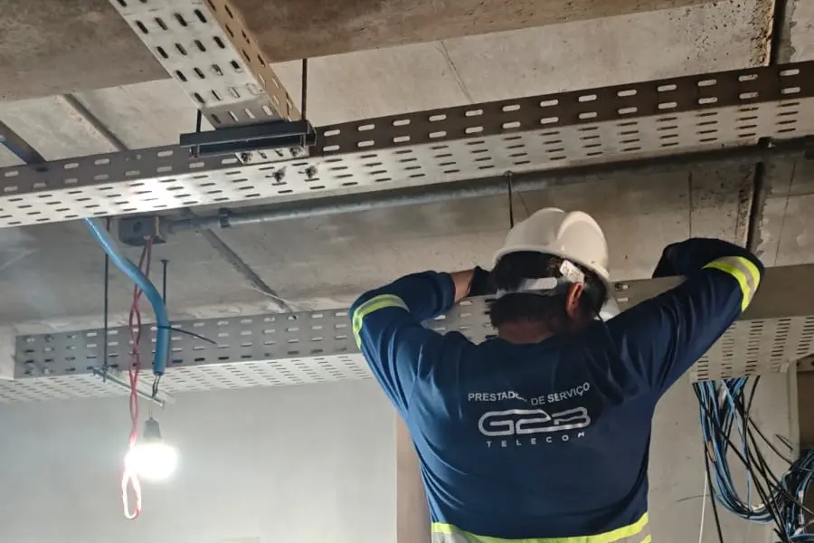 Técnico da G2B passando cabos na eletrocalha em obra